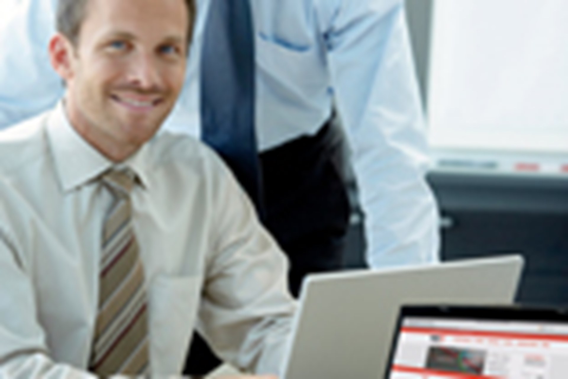 Intraday-Handel Zwei Männer im Büro schauen sich gemeinsam etwas auf dem Laptop an.