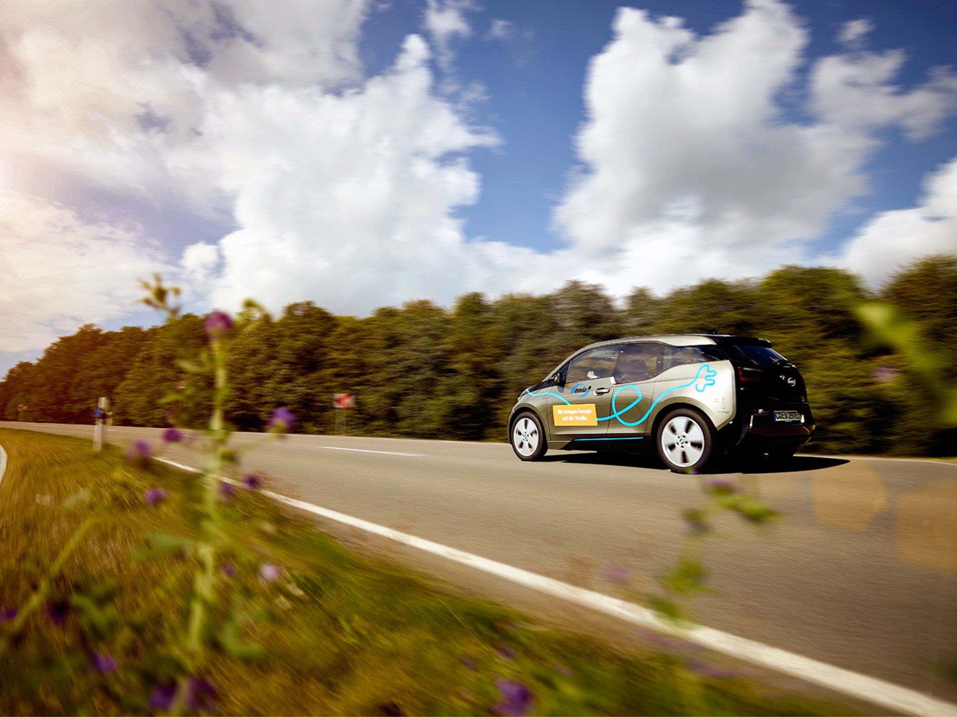 Autostrom Ein Elektroauto fährt auf einer Landstraße.